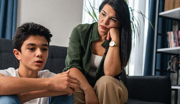 Son on floor mother on couch after quarrel at home
